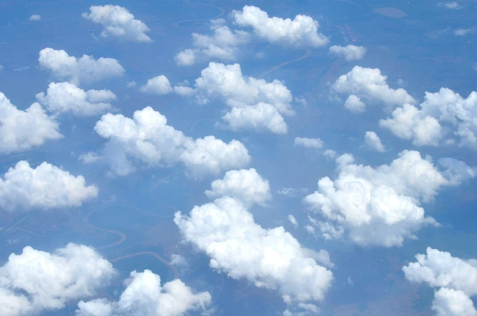 Fluffy white clouds float in a bright blue sky.